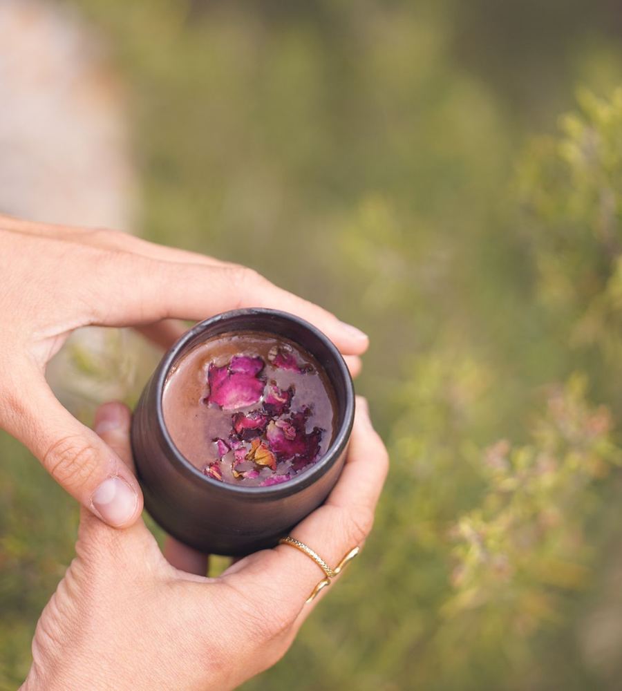 A hand holding a cup of cacao outdoors