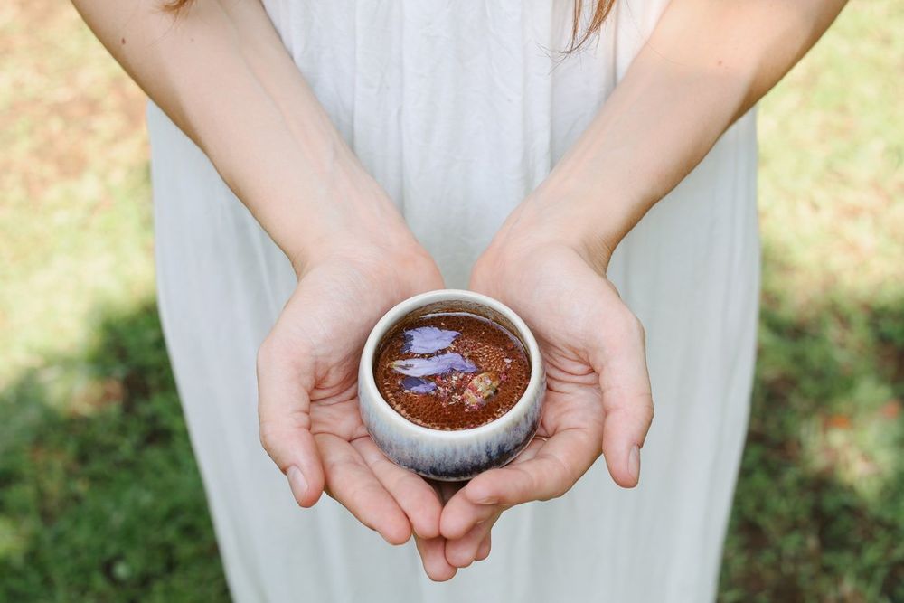 Hands holding a cup of ceremonial cacao